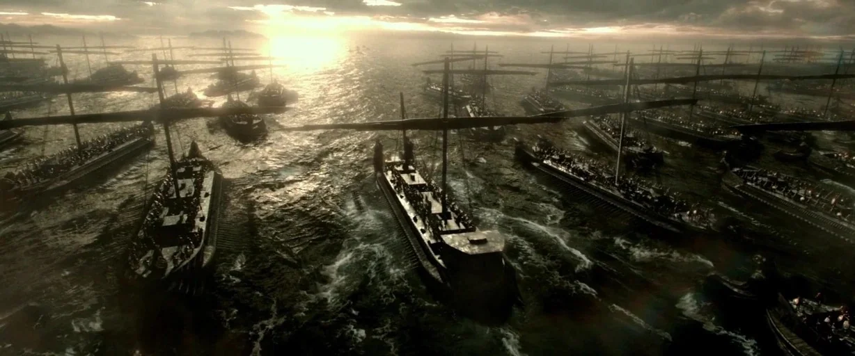 300: Rise of an Empire (2014) movie still: establishing — A vast fleet of ancient wooden warships sails in unison across a dark sea. The low sun…