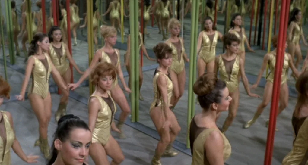 Dr. Goldfoot and the Girl Bombs (1966) movie still: fullbody — A spacious room filled with vertical mirrors and thin red and green support poles. A…
