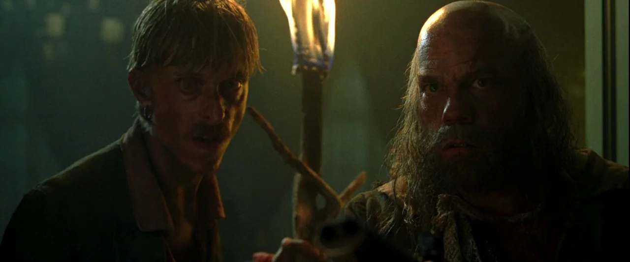 Pirates of the Caribbean: The Curse of the Black Pearl movie still: medium — The dark, enclosed space features stone or concrete walls covered in…