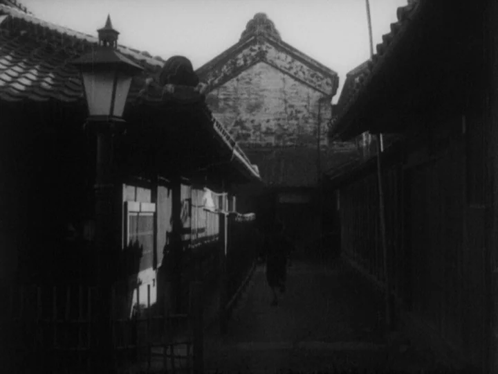 Sanshiro Sugata (1943) movie still: wide — A narrow alleyway sits between dark traditional Japanese wooden buildings at night. An ornate, vintage…