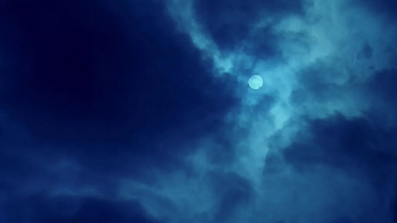 The Bride with White Hair II (1993) movie still: establishing — Dark storm clouds fill the frame, partially obscuring the bright full moon. Wisps of…