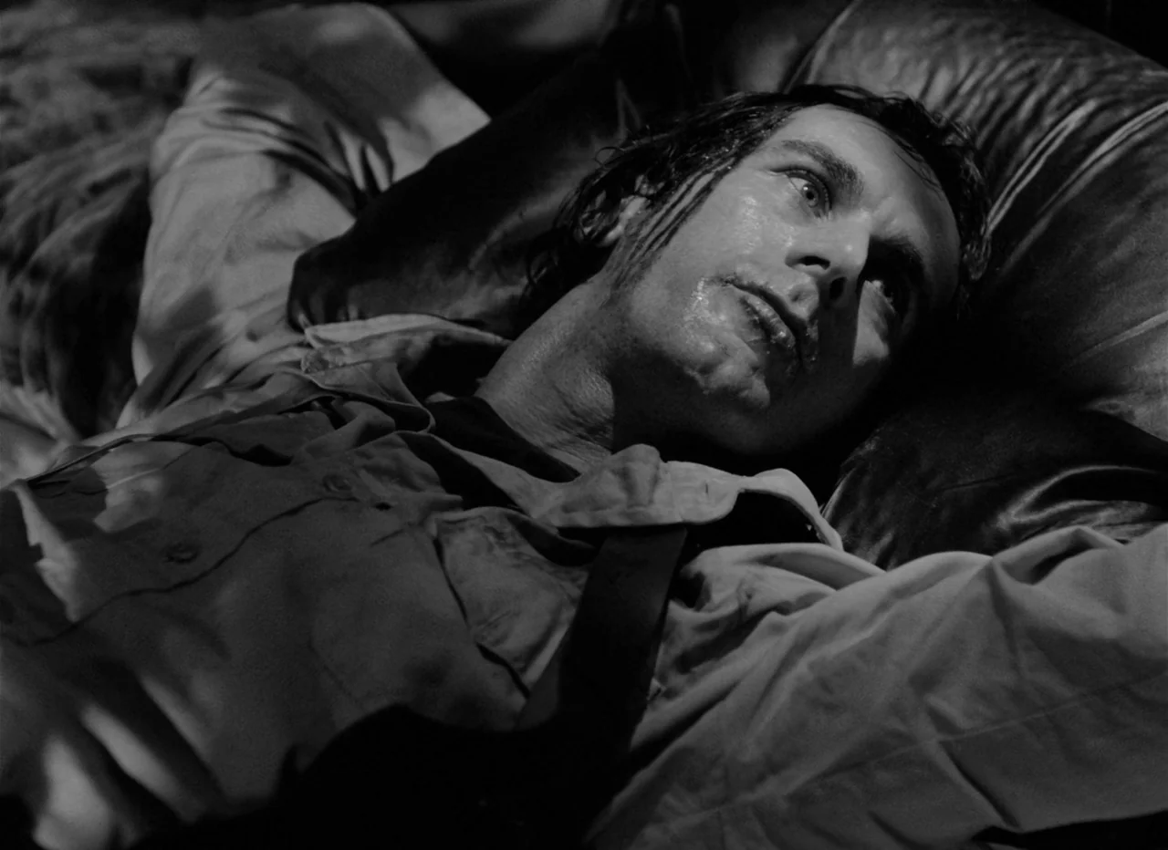 Singapore Sling (1990) movie still: closeup — A man lies on a pillow in a darkened environment. He gazes upward with a fixed expression.