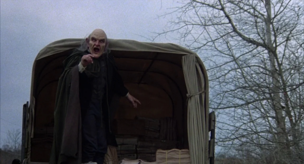 Creepshow 2 (1987) movie still: medium — A man stands inside a canvas-covered wagon on a cold, overcast day. The subject shouts while gesturing,…