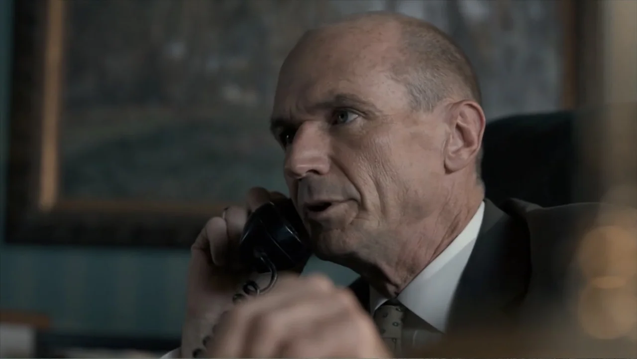 All the Way (2016) movie still: closeup — A dimly lit office features dark wallpaper and a framed picture on the wall. A middle-aged man in a suit…