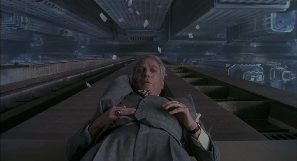 The Hudsucker Proxy (1994) movie still: medium — An elderly man lies flat on a concrete ledge of an incredibly high skyscraper. Dozens of white…