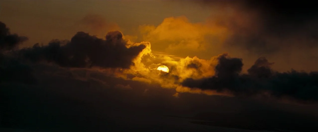 Harry Potter & The Order of the Phoenix (2007) movie still: establishing — A dark, cloud-filled sky features the bright orb of the sun partially…
