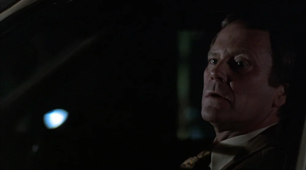 Hardcore (1979) movie still: closeup — An older man sits in the dark interior of a car at night. He stares through the window with a concerned and…