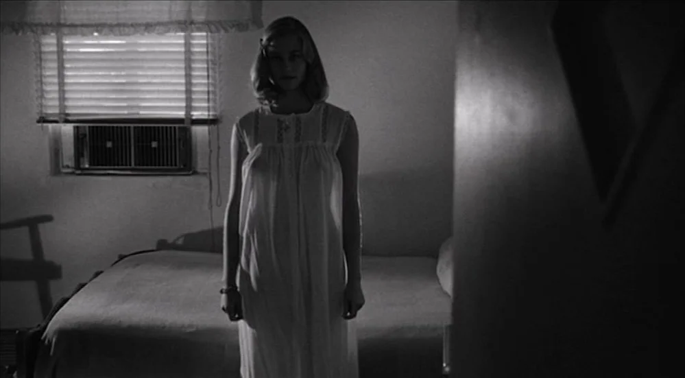 The Last Picture Show (1971) movie still: fullbody — A dimly lit room features a bed and a window with Venetian blinds. A woman wearing a white…