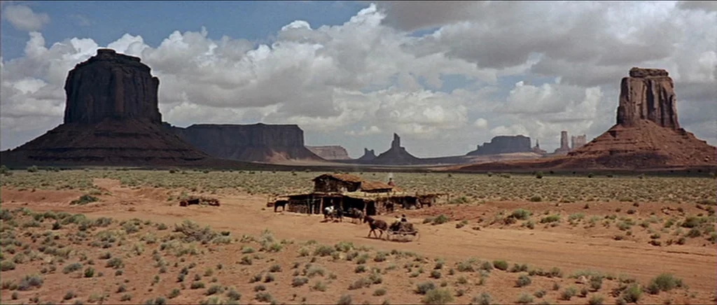 Once Upon A Time In The West (1968) movie still: establishing — A vast desert valley features towering sandstone buttes against a sky with white…
