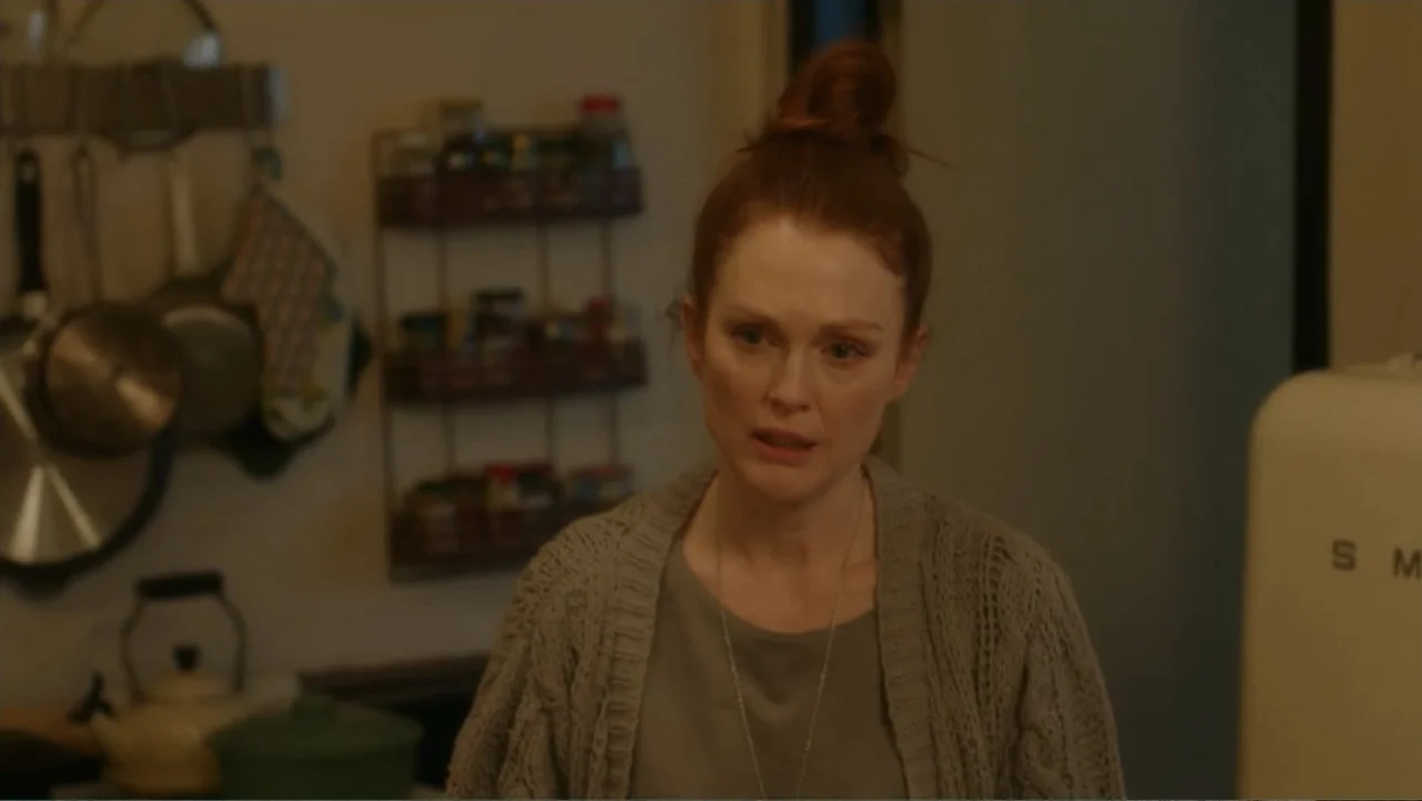 Maggie's Plan (2016) movie still: medium — A residential kitchen features white walls, hanging kitchen utensils, and a cream-colored refrigerator. A…