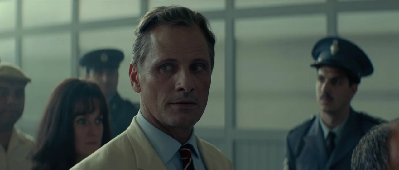The Two Faces of January (2014) movie still: medium — An airport terminal with large grid-patterned windows and uniformed officials in the…