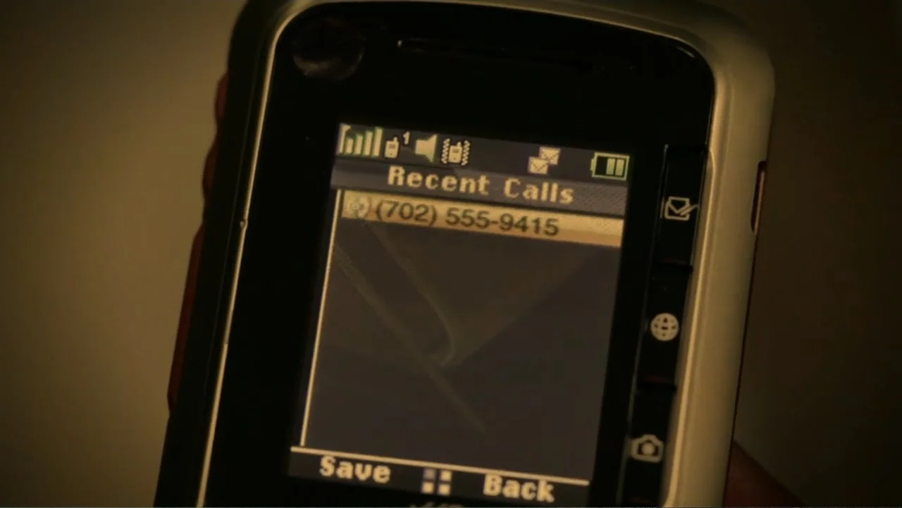 The Messenger (2015) movie still: closeup — A close-up view shows a handheld mobile phone screen in a dim environment. The screen displays a recent…
