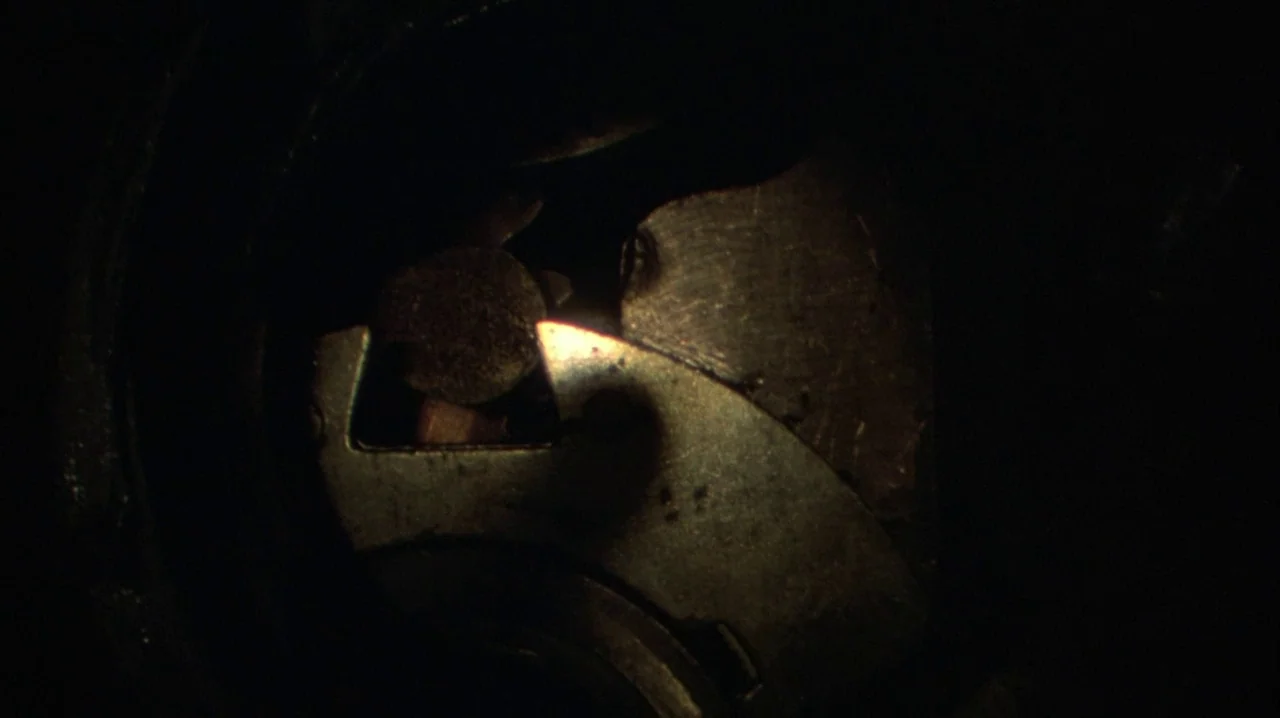 Thief (1981) movie still: closeup — A close-up view shows the interior of a mechanical film camera. A metallic shutter blade remains partially…