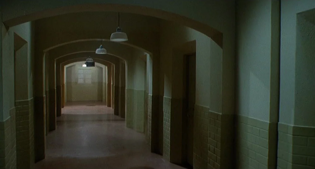 Blood From The Mummy’s Tomb (1971) movie still: establishing — A long institutional hallway features arched ceilings and walls with tan tiled lower…