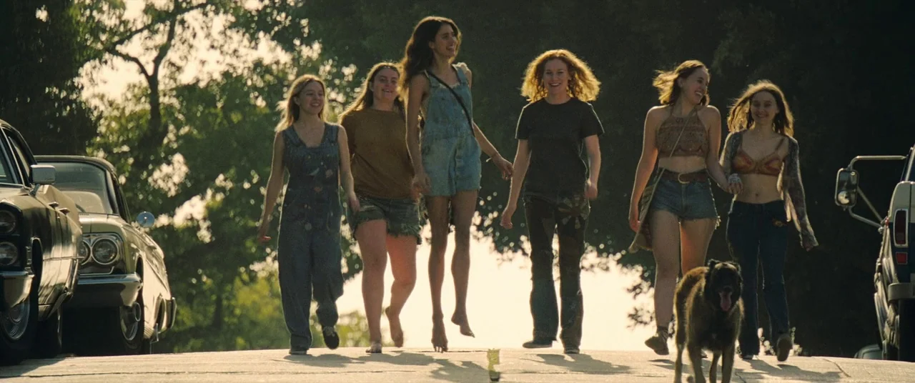 Once Upon a Time… In Hollywood (2019) movie still: wide — A group of women walk together down a sunny residential street near vintage cars. The…