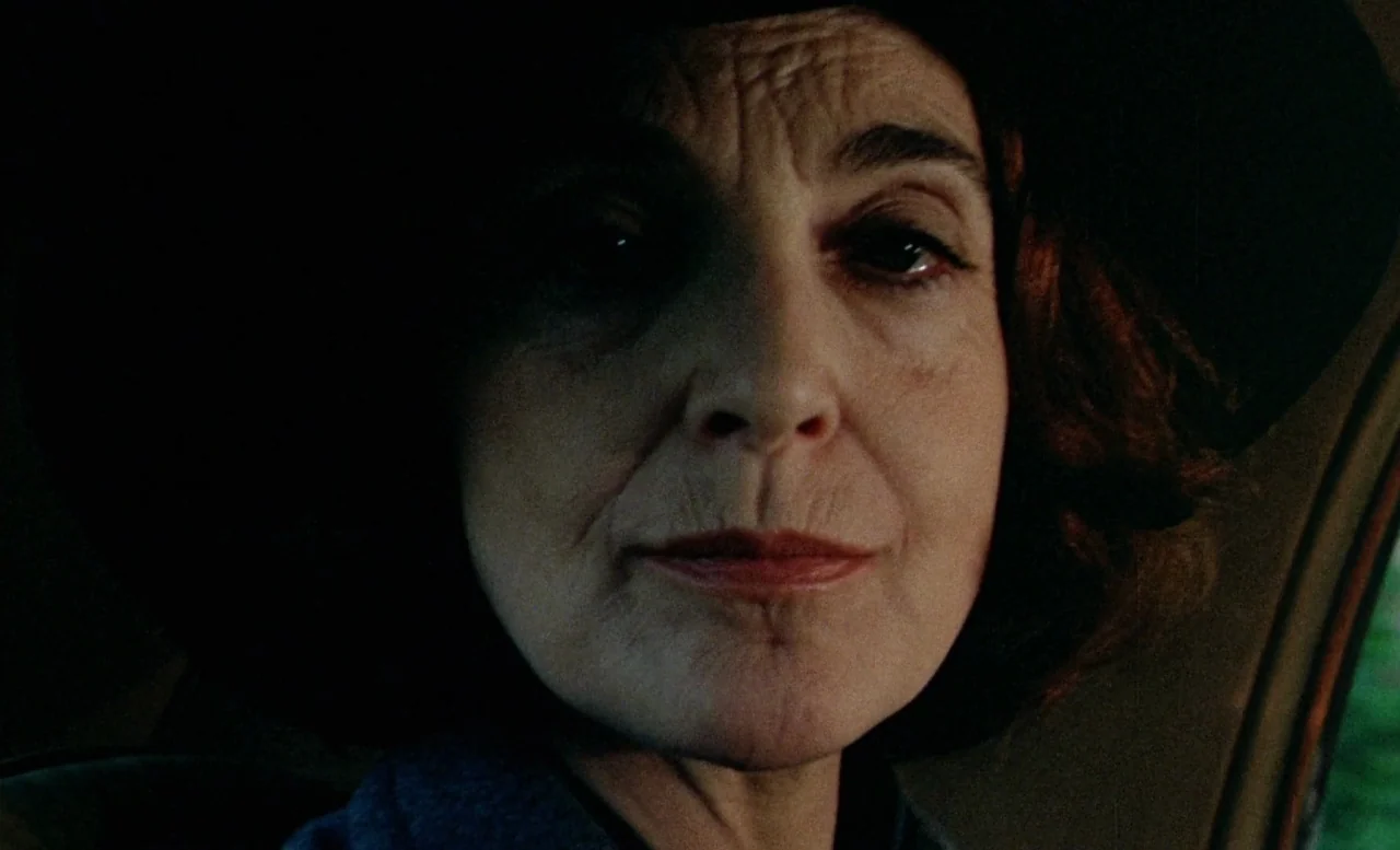 The Beast (1975) movie still: closeup — The interior of a car where a mature woman sits in the driver seat. She is framed in a close-up while…