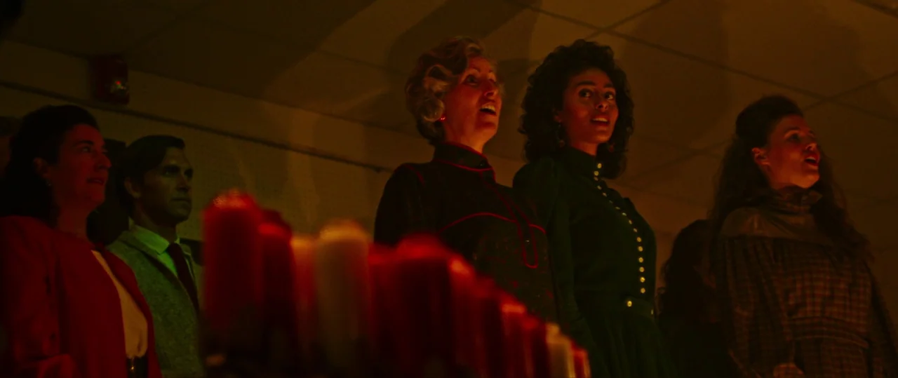 Random Acts of Violence (2019) movie still: medium — A group of people stands in a dim room illuminated by a row of candles. They are gathered in a…