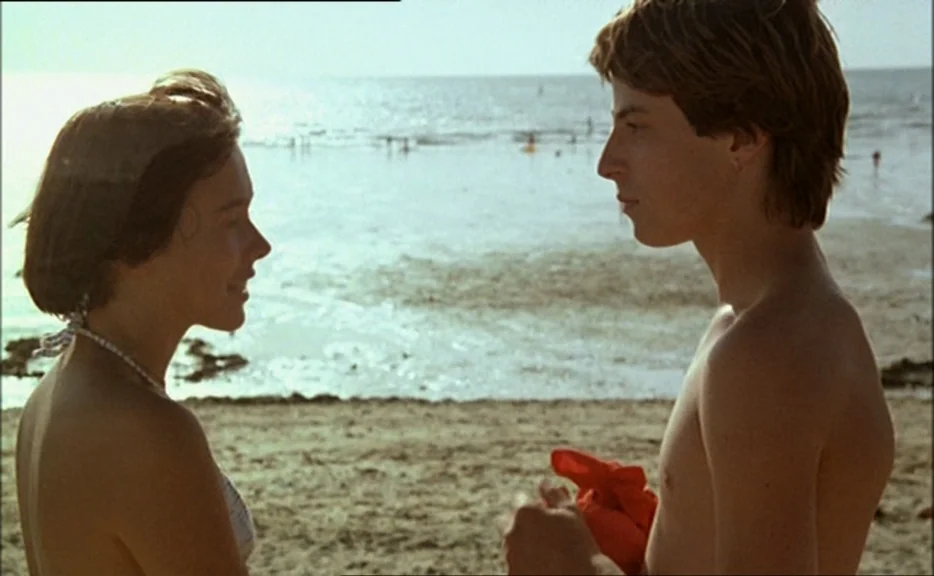 Pauline At the Beach (Pauline à la plage) (1983) movie still: medium — A sunny beach with a calm shoreline in the background during the day. A young…