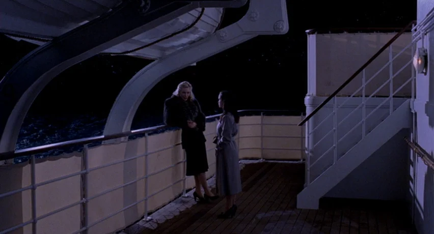 The Man Who Cried (2000) movie still: wide — An exterior deck of a ship at night with dark ocean waves visible. Two women face each other while…