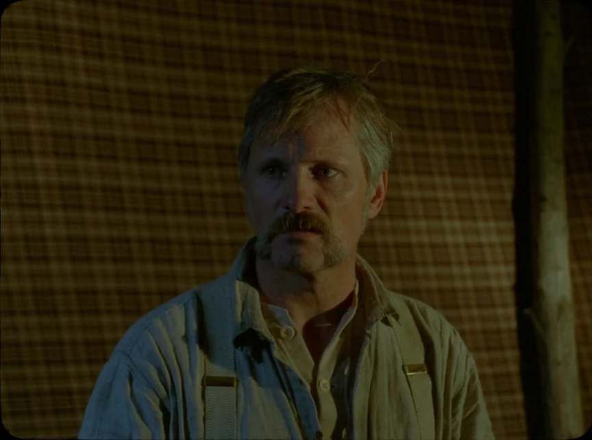Jauja (2014) movie still: medium — The interior of a fabric tent features a plaid textured wall behind the subject. A middle-aged man with a…