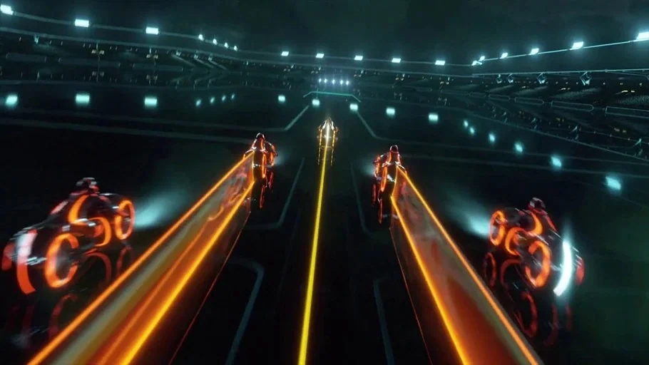 TRON: Legacy (2010) movie still: wide — A dark reflective surface spans out under a vast digital sky with illuminated grid lines. Four motorcyclists…