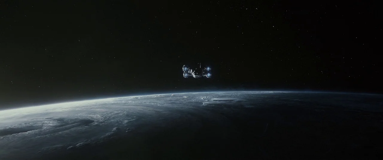 Prometheus (2012) movie still: establishing — A dark, expansive outer space environment features a curvature of a cloud-covered planet below. A…