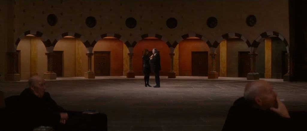 You Ain’t Seen Nothin’ Yet (2012) movie still: wide — An expansive atrium features a line of arched doorways with ornate decorative motifs. A man…