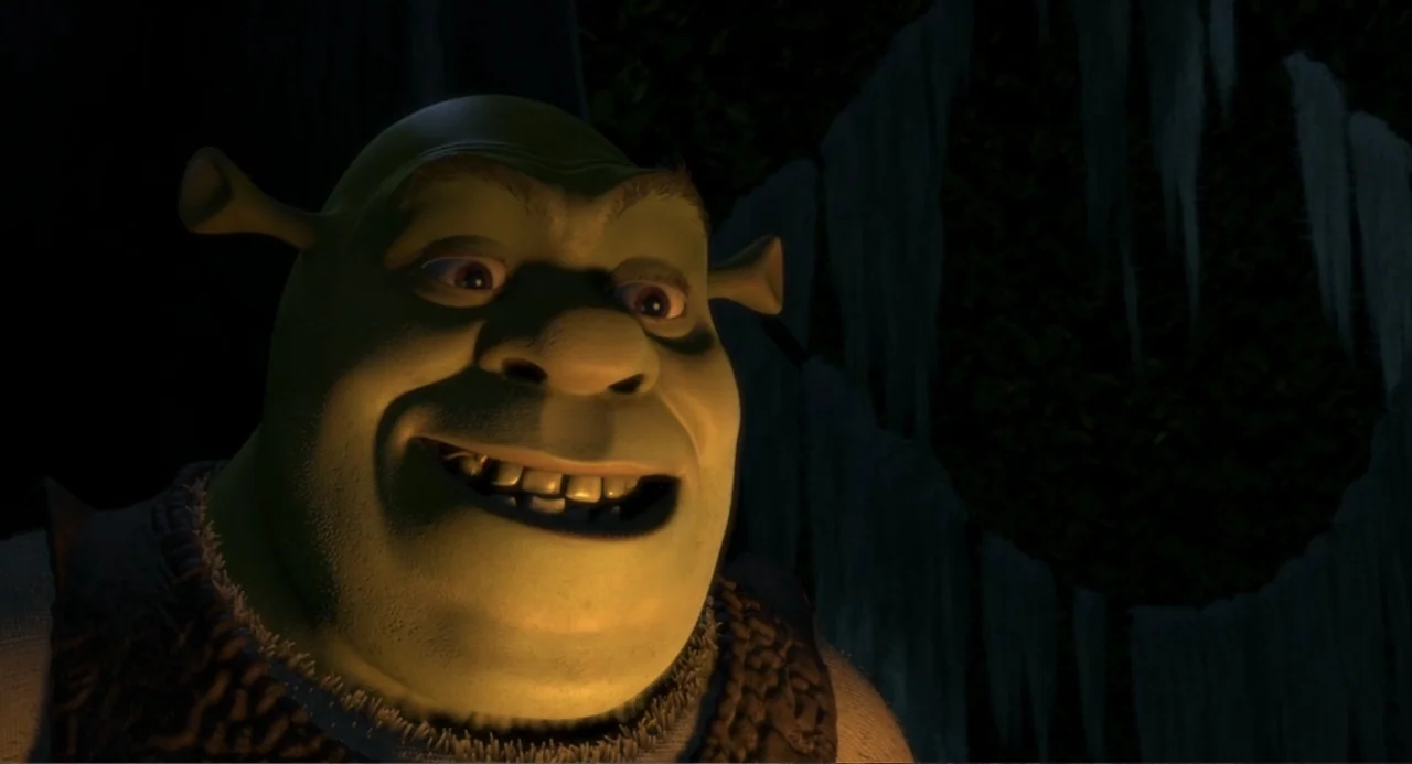 Shrek (2001) movie still: closeup — A dark, dimly lit environment features a green creature with distinctive ears and skin. The subject turns…
