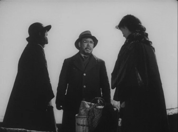 Drunken Angel (1948) movie still: medium — Three individuals stand in an open, featureless field against a bright, hazy sky. They appear to be…
