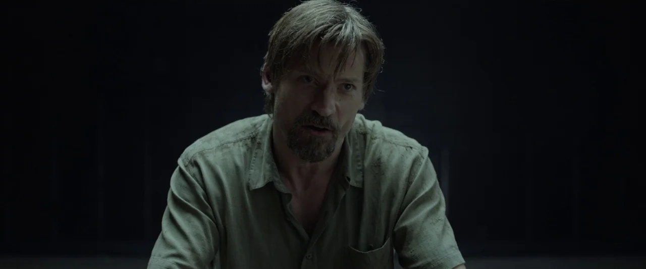 Small Crimes (2017) movie still: medium — A man sits alone in a completely black and featureless room. He speaks directly forward while illuminated…