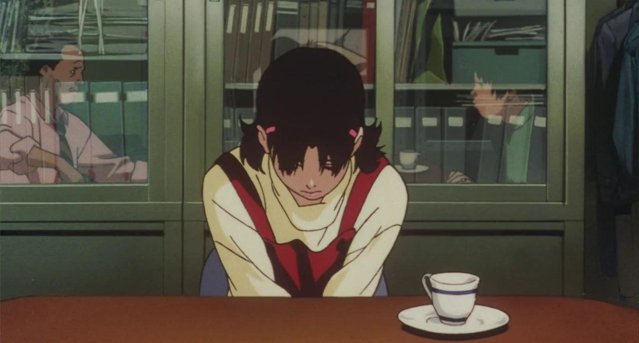 Perfect Blue (1997) movie still: medium — A staff room contains green metal filing cabinets with glass doors and inner binders. A young woman with…