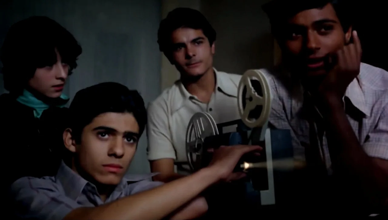 Alexandria…Why? (1979) movie still: medium — A dark, dimly lit room contains four teenage boys gathered around a film projector. The subjects watch…