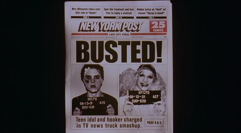 Hedwig and the Angry Inch (2001) movie still: closeup — A New York Post newspaper front page displays the headline BUSTED! in bold letters. Below…