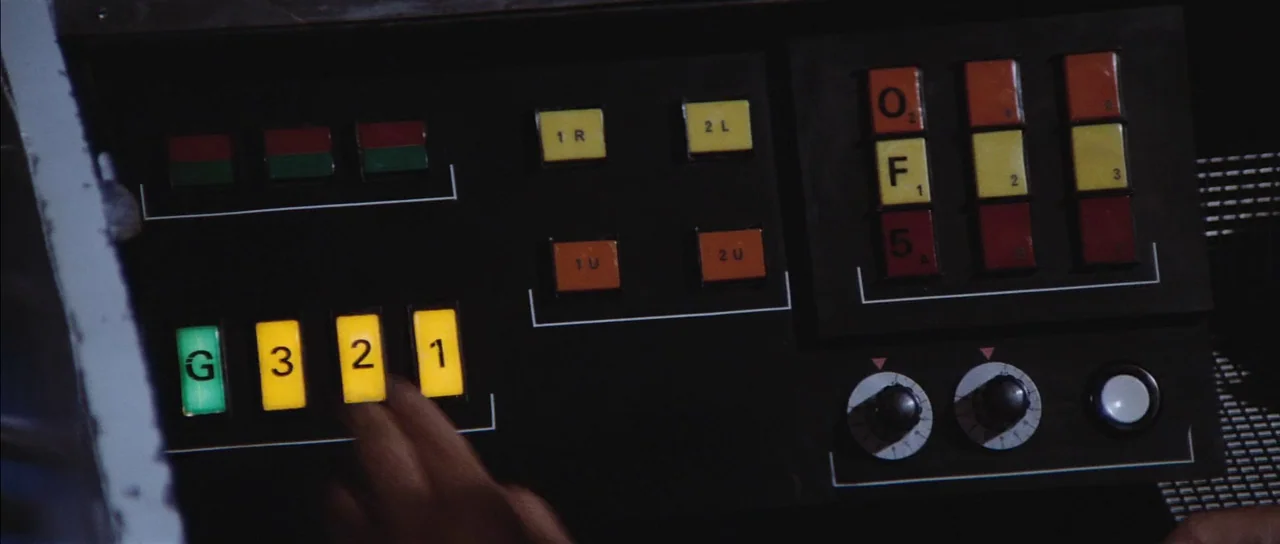 Diamonds Are Forever (1971) movie still: closeup — A dark console panel features rows of square, backlit buttons with numbers and letters. A hand…