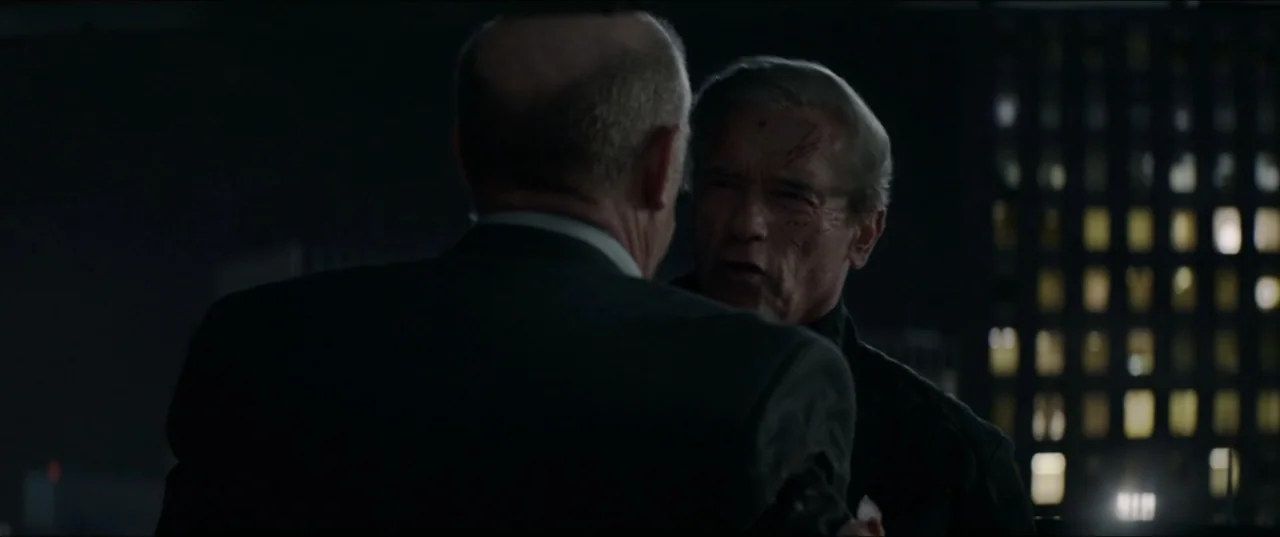 Terminator Genisys (2015) movie still: medium — A dimly lit room overlooks a dark city at night with illuminated windows visible. Two older men…