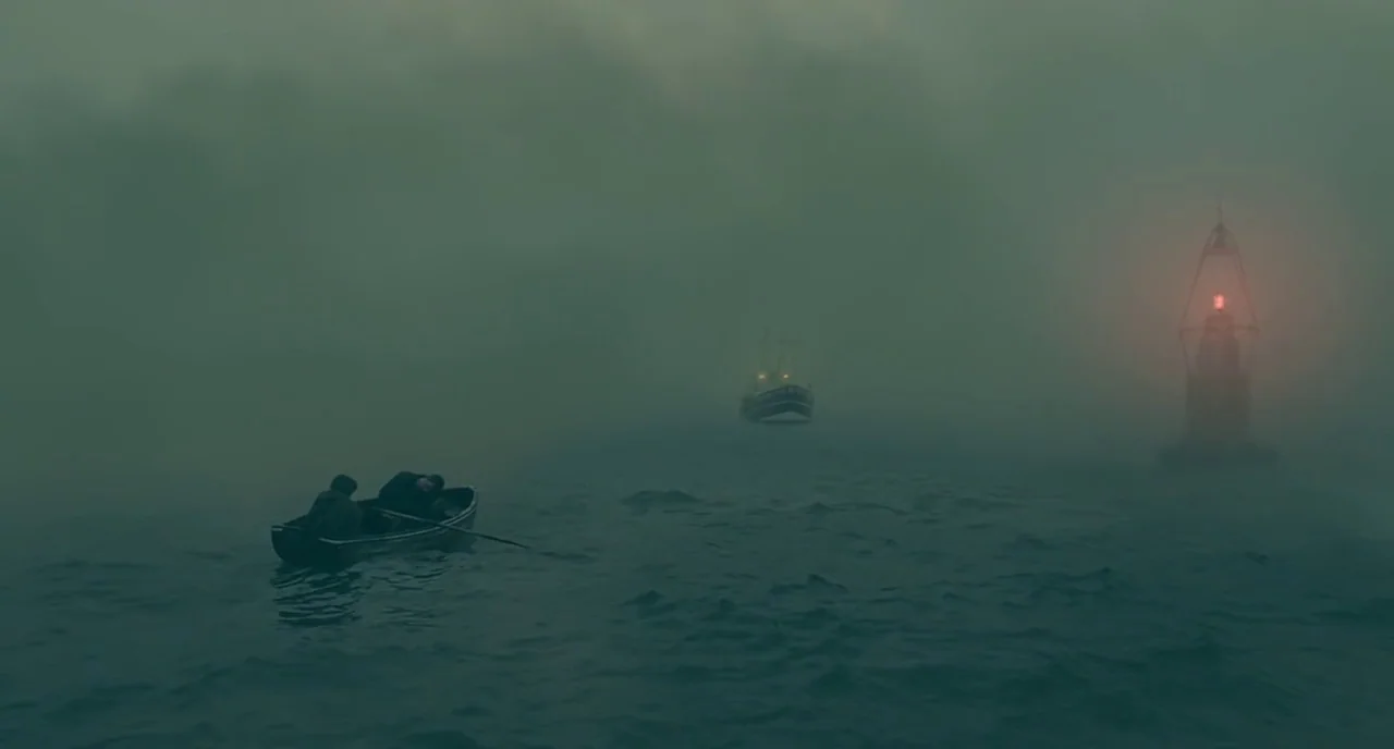 Children Of Men (2006) movie still: wide — A dark, foggy expanse of open water at night with low visibility. Two people sit in a small rowboat near…