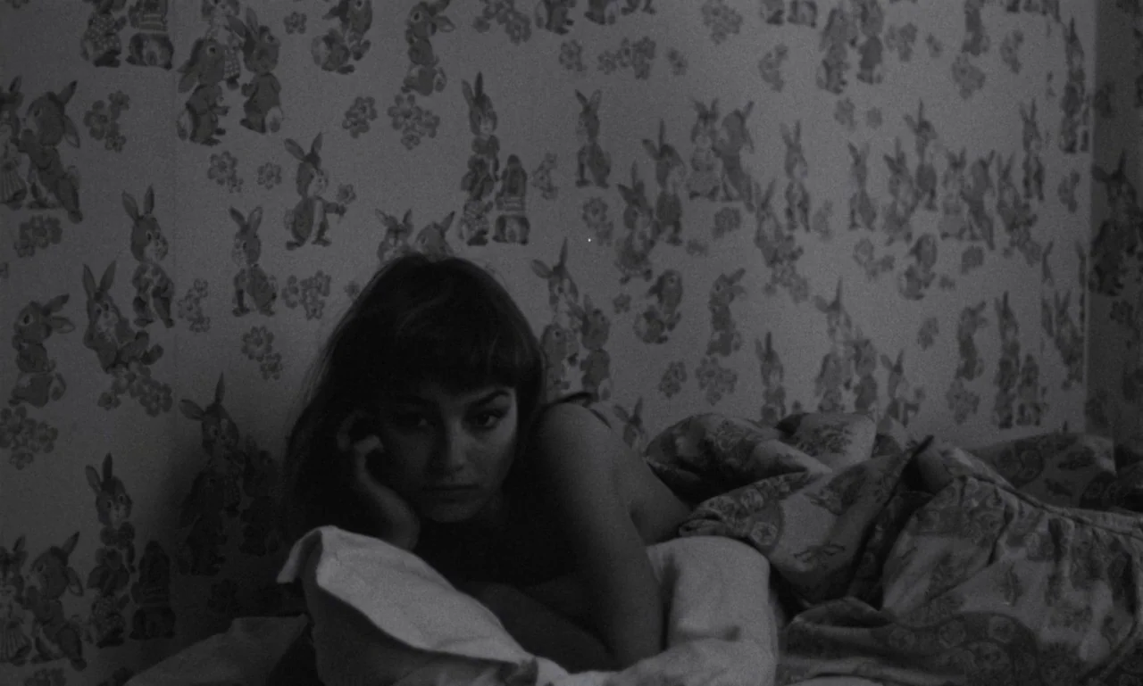 The Secret Son (1979) movie still: medium — A woman lies in a bed against a wall decorated with rabbit pattern wallpaper. She rests her head on her…