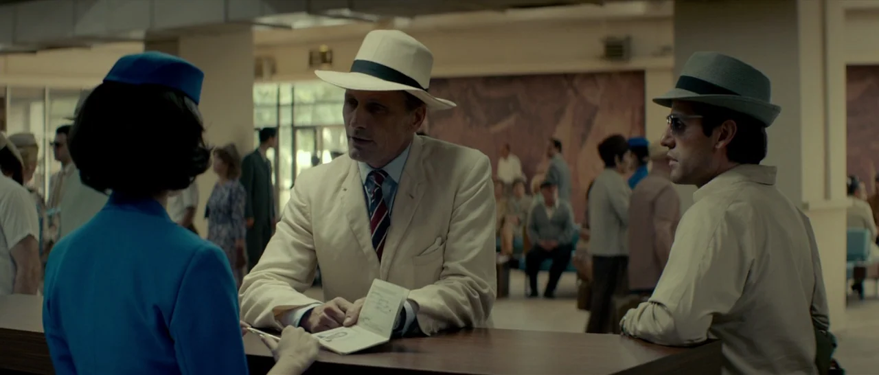 The Two Faces of January (2014) movie still: medium — A busy airport terminal check-in area features mid-century modern architecture and blurred…