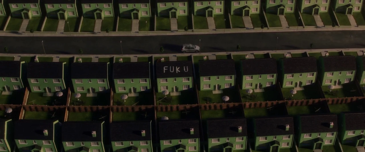 Vivarium (2019) movie still: establishing — A dense grid of uniform green houses features repeating layouts and small fenced yards. One rooftop…