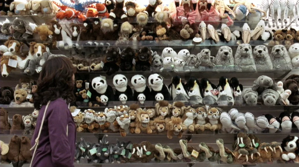 Year Of The Dog (2007) movie still: medium — A wall of shelves in a toy store is stocked with many plush animals. A woman wearing a purple jacket…