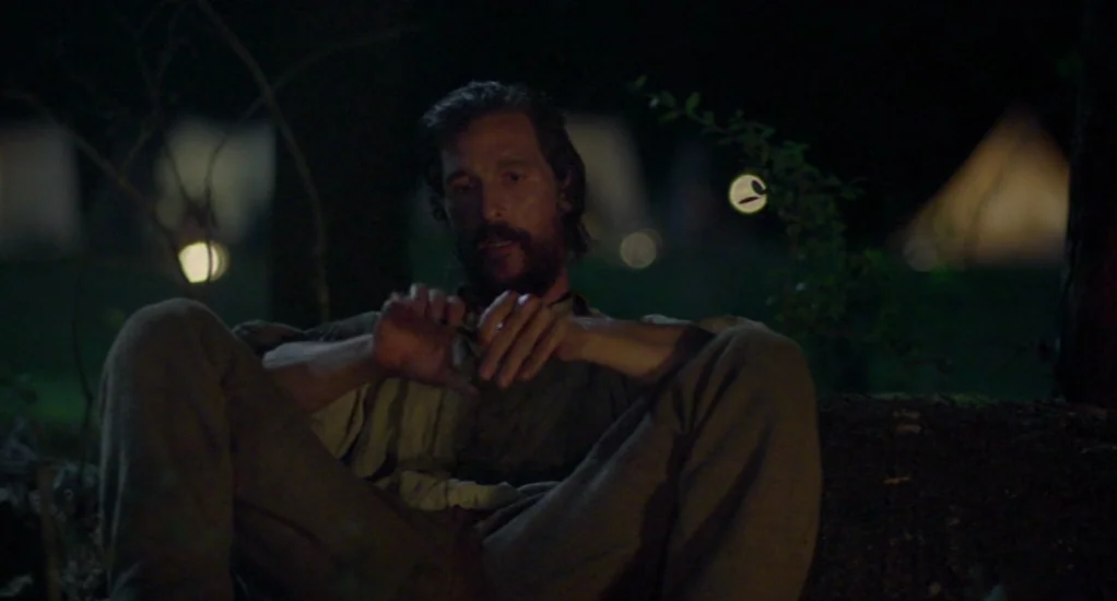 Free State of Jones (2016) movie still: medium — A dimly lit outdoor encampment at night features multiple soft-glowing tents in the distance. A man…