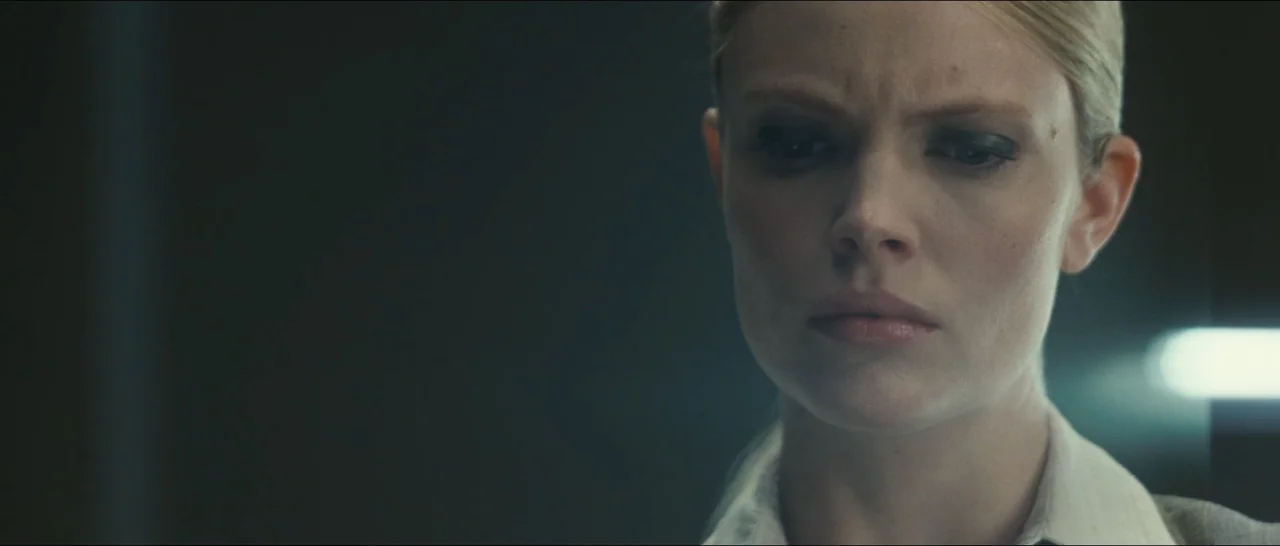 Slackers (2002) movie still: closeup — A darkened office interior features a woman in front of a soft light source. She stares past the camera with…