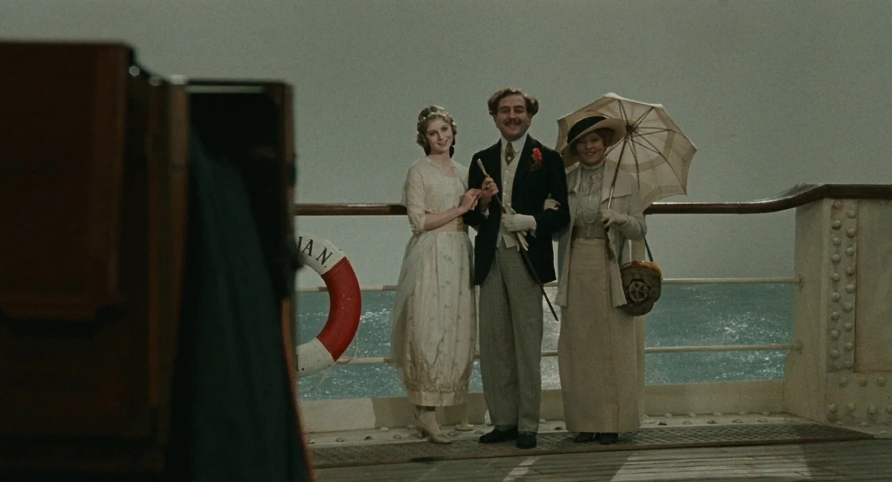 And The Ship Sails On (1983) movie still: fullbody — A group of three people stands on the wooden deck of a passenger ship. They pose for a…