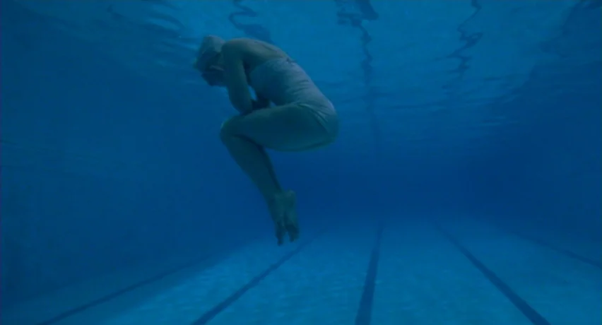 The Man Who Cried (2000) movie still: fullbody — An empty underwater view of a standard public swimming pool with dark lane lines. A single person…