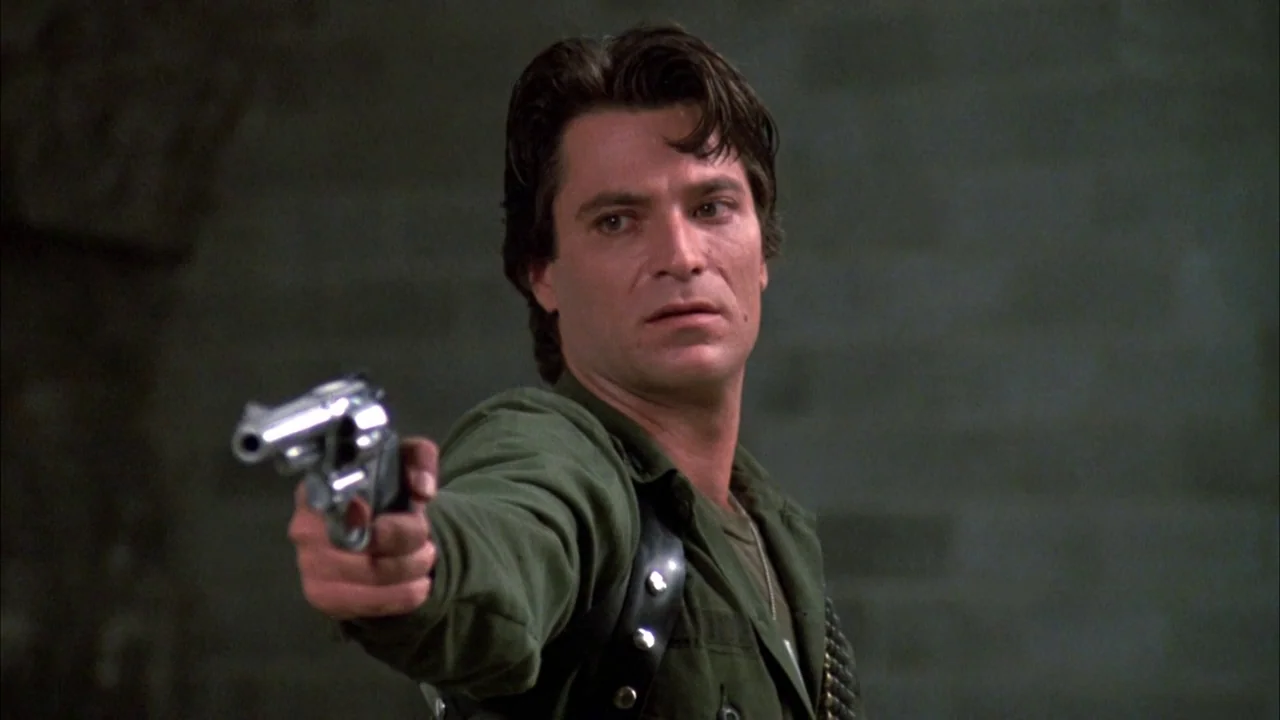 Day of the Dead (1985) movie still: medium — A dimly lit interior space features a stone wall backdrop and low-contrast shadow. A man stands in the…