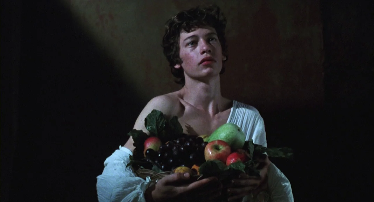 Caravaggio (1986) movie still: medium — A dark, empty space with a single person positioned in the foreground. The person holds a large wicker…