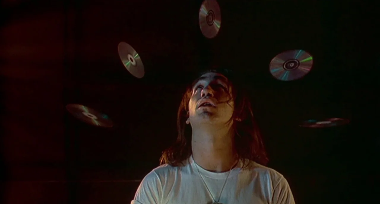 Hellraiser III: Hell on Earth movie still: medium — A man stands in an undifferentiated dark space with no visible architectural details. Several…