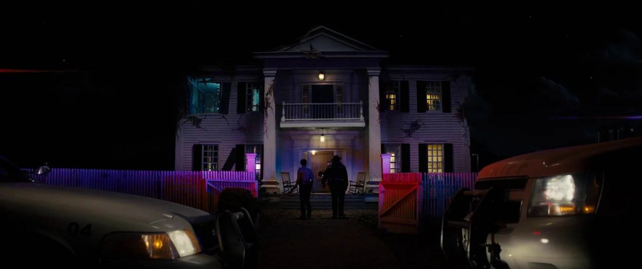 Brightburn (2019) movie still: wide — A two-story white clapboard house at night is illuminated by red and blue lights. Two uniformed police…