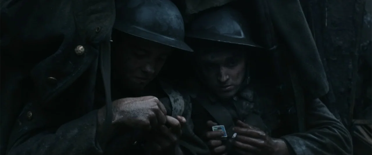 Freud's Last Session (2023) movie still: medium — Two soldiers in wet, muddy uniforms huddle together inside a cramped, dark trench. They examine a…