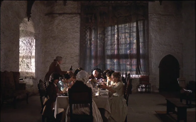 Barry Lyndon (1975) movie still: wide — A stone-walled hall with rough masonry features a large wall tapestry and arched doorways. Multiple people…